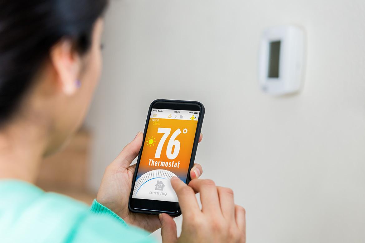 Woman programming smart thermostat